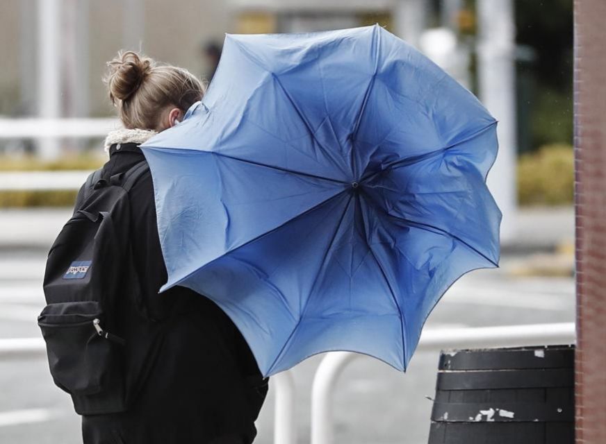 Una mujer intenta que el viento no arrastre su paraguas ayer en...
