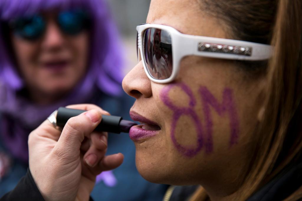 Una mujer se pinta los labios de morado con motivo del 8-M en Madrid