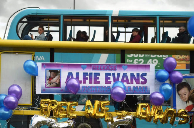 A bus passes balloons and posters left in support of British toddler Alfie Evans, on a bus-stop opposite Alder Hey childrens hospital in Liverpool, north-west England on April 26, 2018. Alfie Evans, who is 22 months old, has a rare degenerative neurological condition which has not been definitively diagnosed. His parents, Tom Evans and Kate James, have fought a legal battle to stop the Alder Hey Children's Hospital in Liverpool, north-west England, from turning off his ventilator. / AFP PHOTO / Oli SCARFF