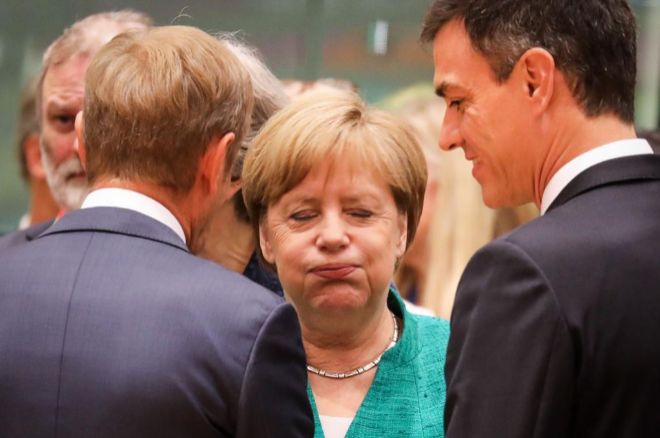 TOPSHOT - Germany's Chancellor Angela Merkel (C) reacts as she speaks with European Council President Donald Tusk (L) and Spain's Prime Minister Pedro Sanchez during an European Union leaders' summit focused on migration, Brexit and eurozone reforms on June 28, 2018 at the Europa building in Brussels. The two-day meeting in Brussels is expected to be dominated by deep divisions over migration, with German Chancellor saying the issue could decide the fate of the bloc itself. / AFP PHOTO / Ludovic MARIN