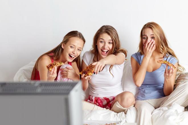adolescentes comiendo pizza y viendo la televisin en el sof.