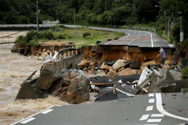 KMA01. Karatsu (Japan), 07/07/2018.- A resident struggles to cross a collapsed road destroyed by heavy train in Higashihiroshima, Hiroshima Prefecture, Japan, 07 July 2018. Heavy rainfall killed at least 15 people and left more than 45 missing, public television reported on 07 July 2018. Japan Meteorological Agency has warned record rainfall on 06 July for flooding, mudslides in southwestern and western Japan through 08 July and issued emergency weather warnings to six prefectures. In nine prefectures in western and southwestern Japan, authorities issued evacuation orders to more than one million people as Typhoon Maria passes the area. (Japn) EFE/EPA/JIJI PRESS JAPAN OUT EDITORIAL USE ONLY NO ARCHIVES