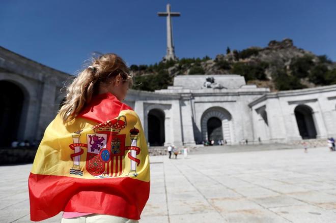 Una mujer, envuelta en una bandera española en la explanada del Valle...