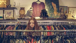 Una chica rebusca entre los percheros de una tienda de moda.