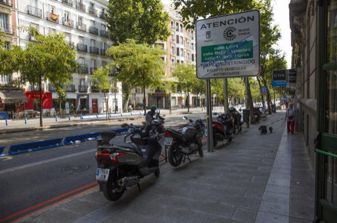 Imagen de varias motos frente a un cartel de Madrid Central