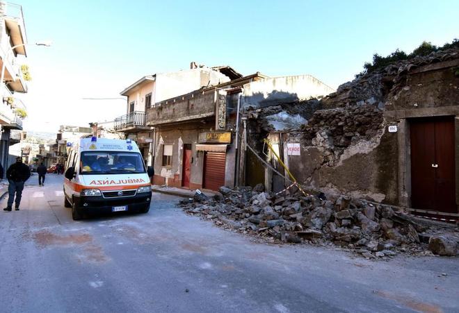 Una ambulancia permanece aparcada junto a una vivienda afectada tras el sesmo en Sicilia.