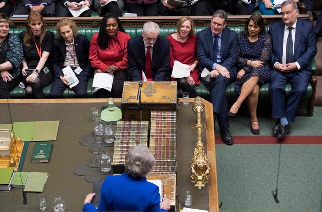 Jeremy Corbyn, en el centro de la bancada, escuchando a Theresa May,...