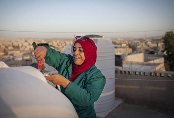 Mariam Tawfeeq Matlaq repara un tanque de agua de la azotea de su casa.