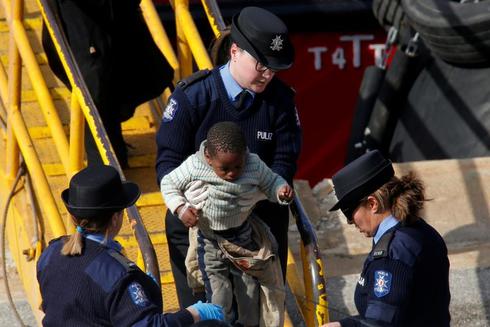Agentes de polica ayudan a los migrantes a desembarcar del buque...
