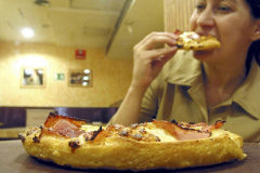 Una mujer come una pizza en una cadena de comida rpida.