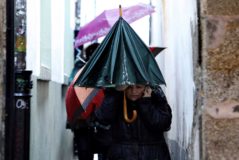Peregrinos y turistas se protegen esta maana de la lluvia en Galicia