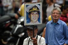 Un hombre sostiene un cartel con la cara del capitn Acosta, torturado y asesinado.