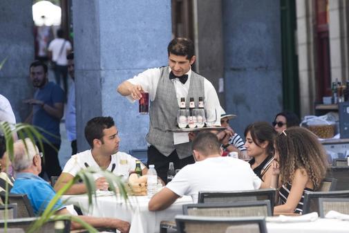 Un camarero atiende a unos clientes en la Plaza Mayor de Madrid.