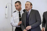 El actor Kevin Spacey custodiado por un polica durante una vista del juicio por agresin sexual.
