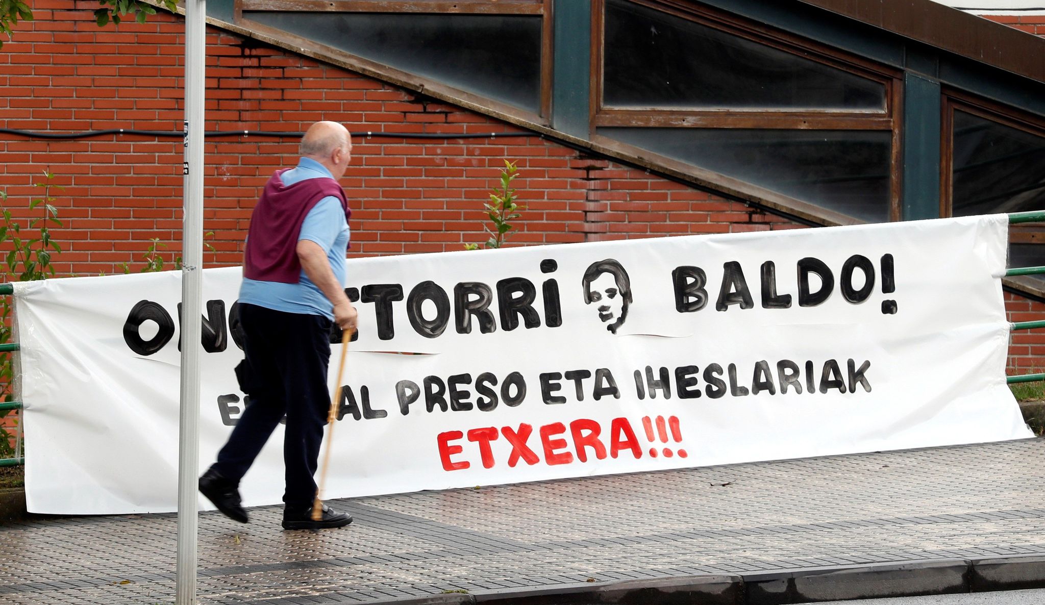 Un vecino camina junto a una pancarta que da la bienvenida a Jos Javier Zabaleta 'Baldo'.