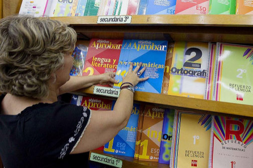Una librera coloca los libros de texto en una estantería.