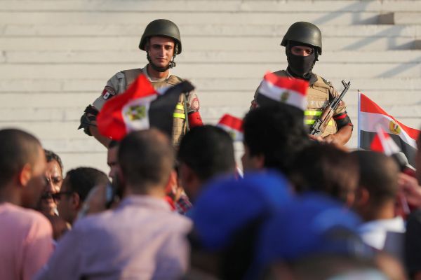 Military police force soldiers watch as supporters of Egyptian...