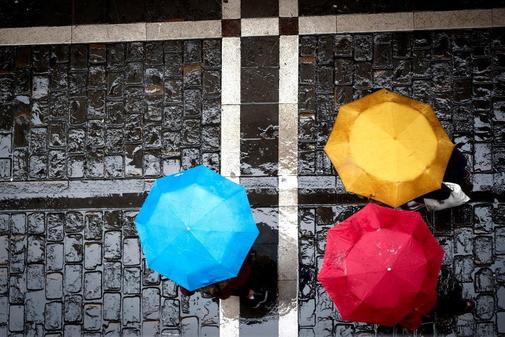 Tres personas se protegan de la lluvia con sus paraguas este sbado...