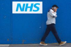 Un hombre pasa junto a un logotipo del Servicio Nacional de Salud (NHS) del Royal London Hospital de  Londres.