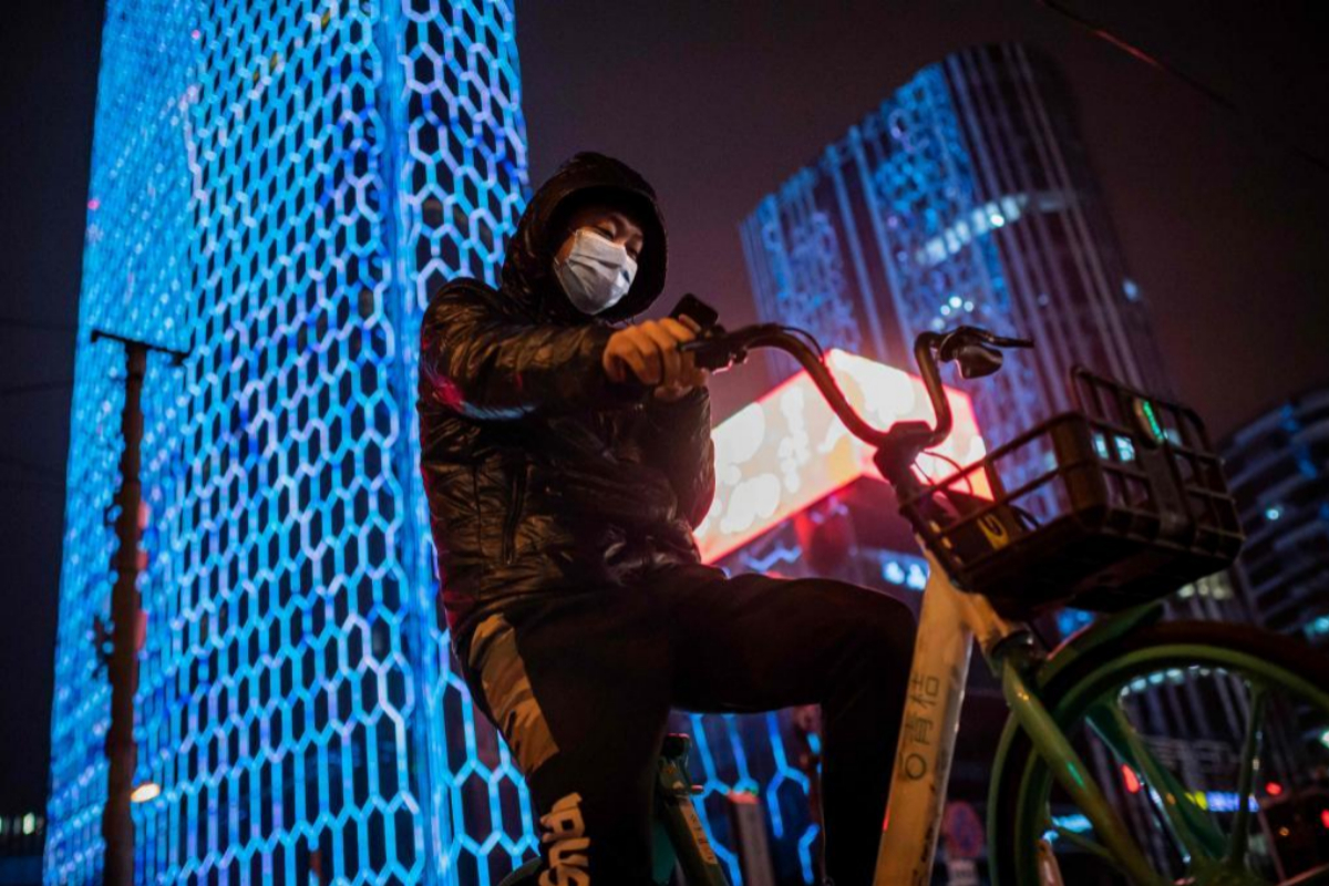 Un hombre con mascarilla protectora pasea en bicicleta por las calles de Pekn.