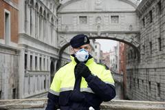 Un agente de polica en Venecia se cubre con una mascarilla.