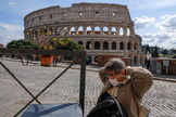 Un turista, frente al coliseo de Roma, se coloca una mascarilla.