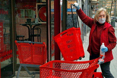 Una trabajadora de un supermercado desinfecta los carritos de la compra