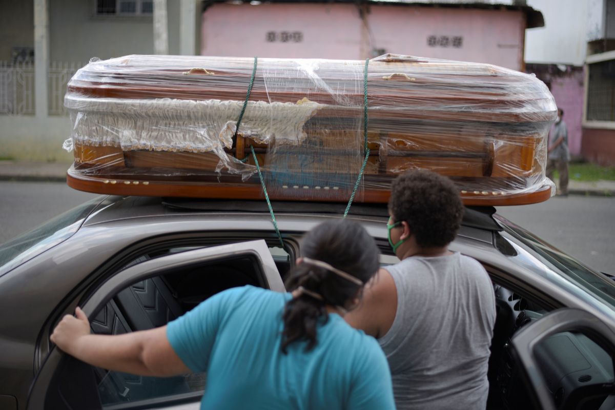 Una pareja lleva el ataúd con un muerto de su familia sobre su coche en Guayaquil.