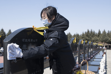 Una mujer limpia una lpida en uno de los cementerios de Harbin (China)