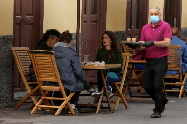 Un camarero atiende a varios clientes en una terraza de un bar de La Laguna (Tenerife).