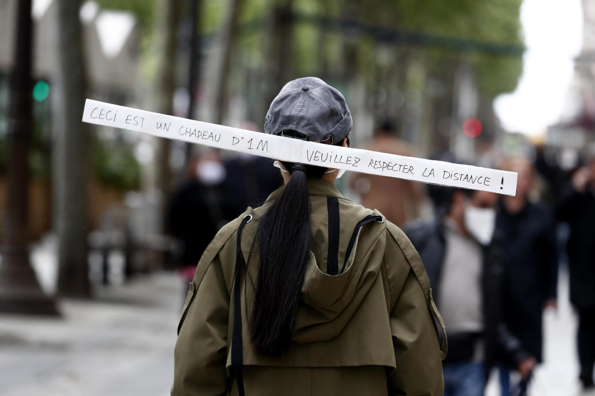 Una mujer utiliza una gorra con una tira de cartn que recuerda la distancia de seguridad.
