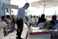Un camarero atiende a los clientes en una terraza de la playa de la Malva-rosa en Valencia.