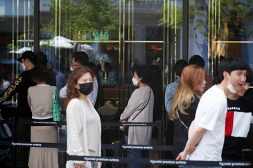 Un grupo de ciudadanos coreanos hacen cola en una tienda de lujo en Gimpo.