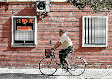 Un hombre pasa por delante de un piso en venta en la barriada sevillana de La Juncal.