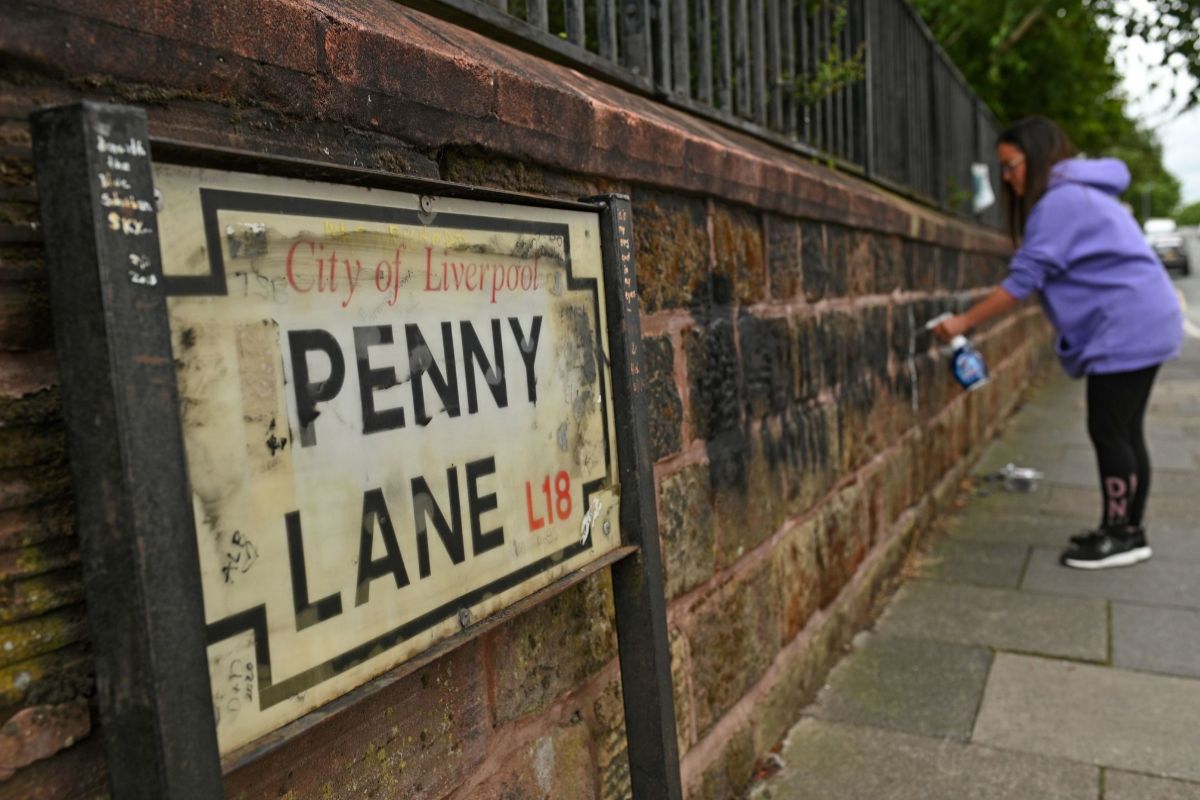 Una vecina limpia las pinturas realizadas en Penny Lane, en in Liverpool.