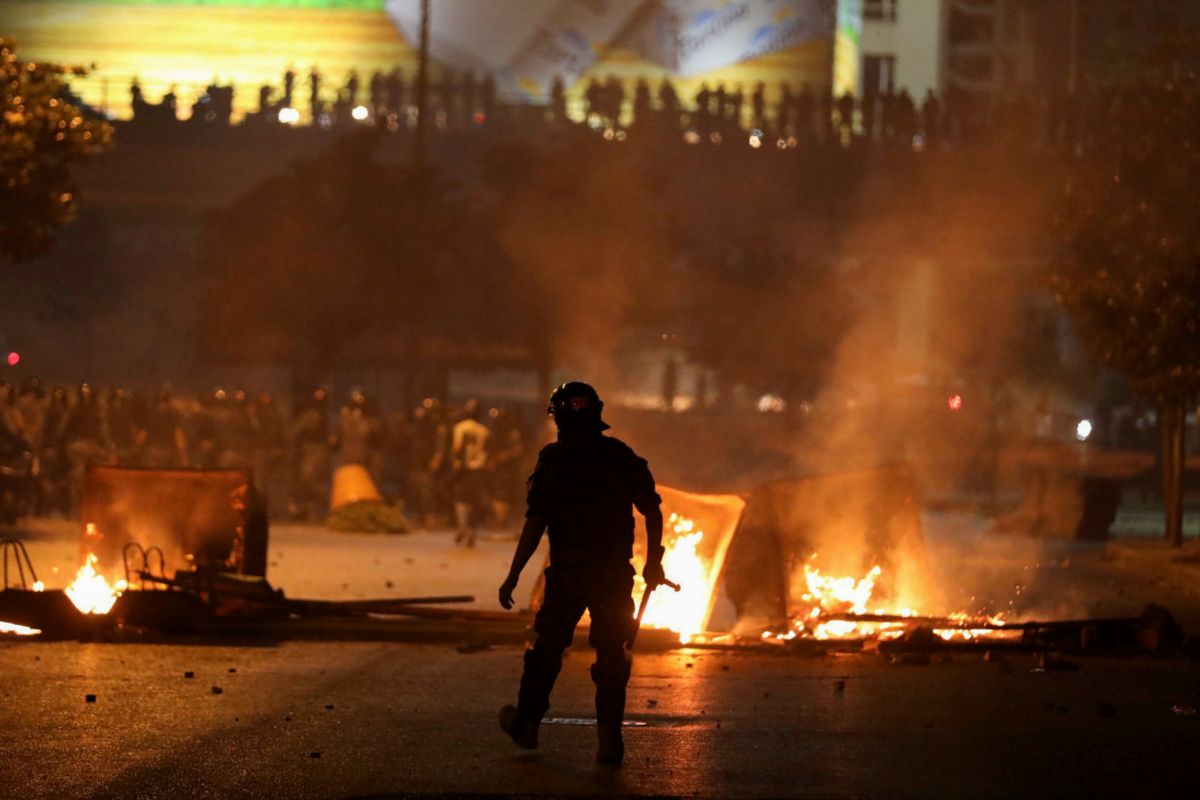 Un agente antidisturbios, frente a una barricada ardiendo durante las protestas del viernes en Beirut.