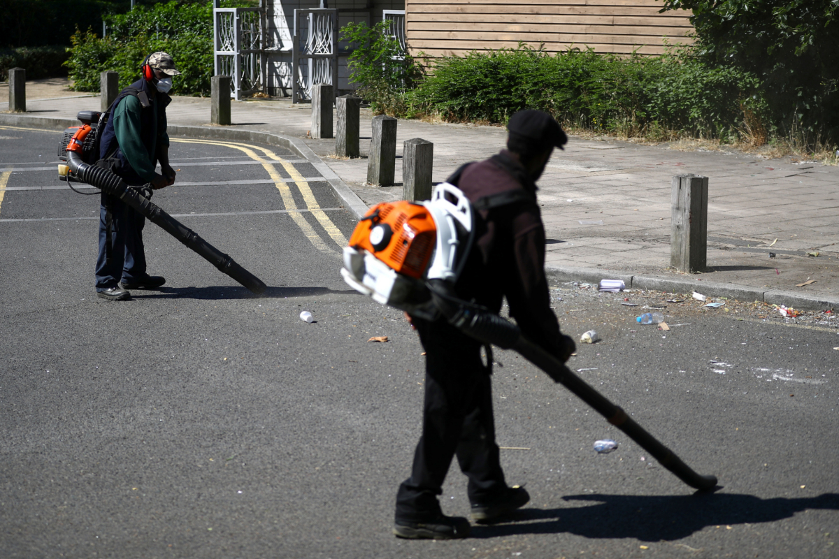 Dos trabajadores limpian la basura en Brixton, donde se celebr la fiesta.