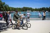 Un padre pasea en bicicleta con su hijo por el Parque de El Retiro de Madrid.