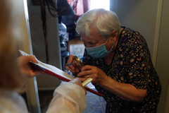 Una mujer con mascarilla rellena el voto desde su casa en Mosc.