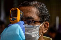 A health worker checks the body lt;HIT gt;temperature lt;/HIT gt; of a resident during a COVID-19 coronavirus screening in Mumbai on August 12, 2020. (Photo by INDRANIL MUKHERJEE / AFP)