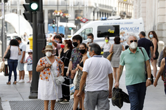 Varias personas pasean, protegidas con mascarilla, por las calles de Madrid.