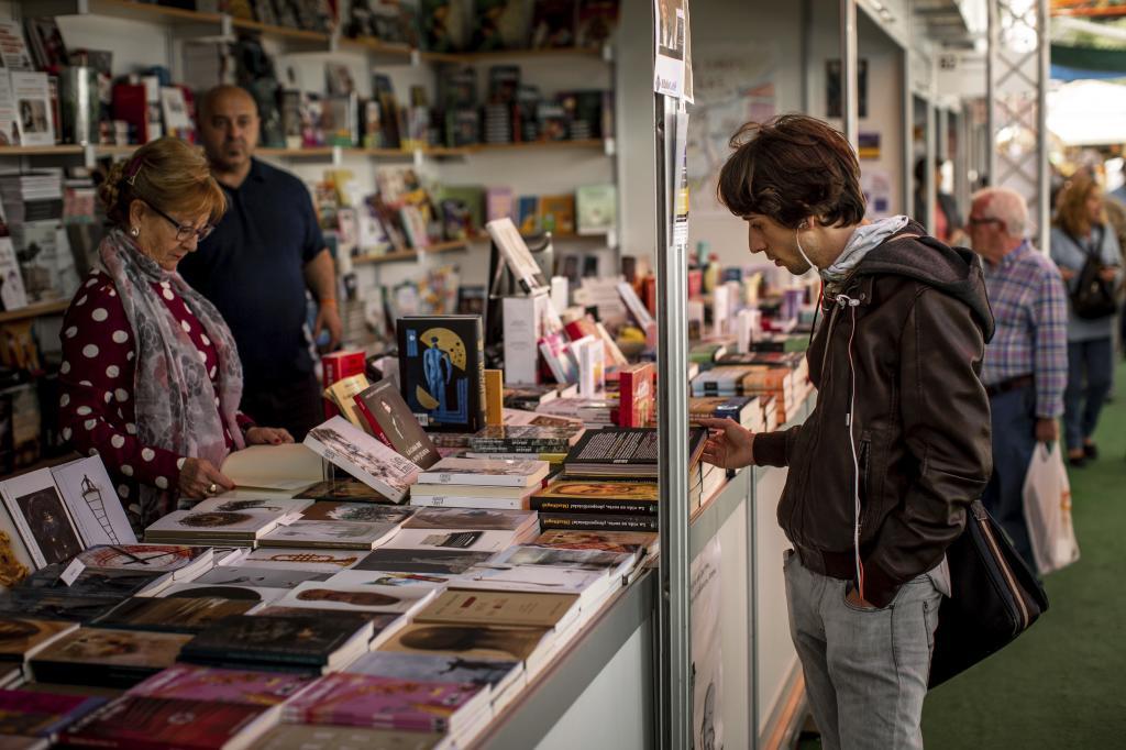 Un hombre ojea un libro en una caseta de la Feria del Libro de Valencia.