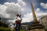 Una mujer camina con recipientes llenos de agua en una plaza de Caracas.