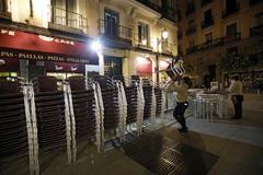 Uno de los restaurantes de la plaza de la Cruz Verde en Madrid comienza a recoger sus mesas antes de las 22:00 horas, por el cierre de la capital.