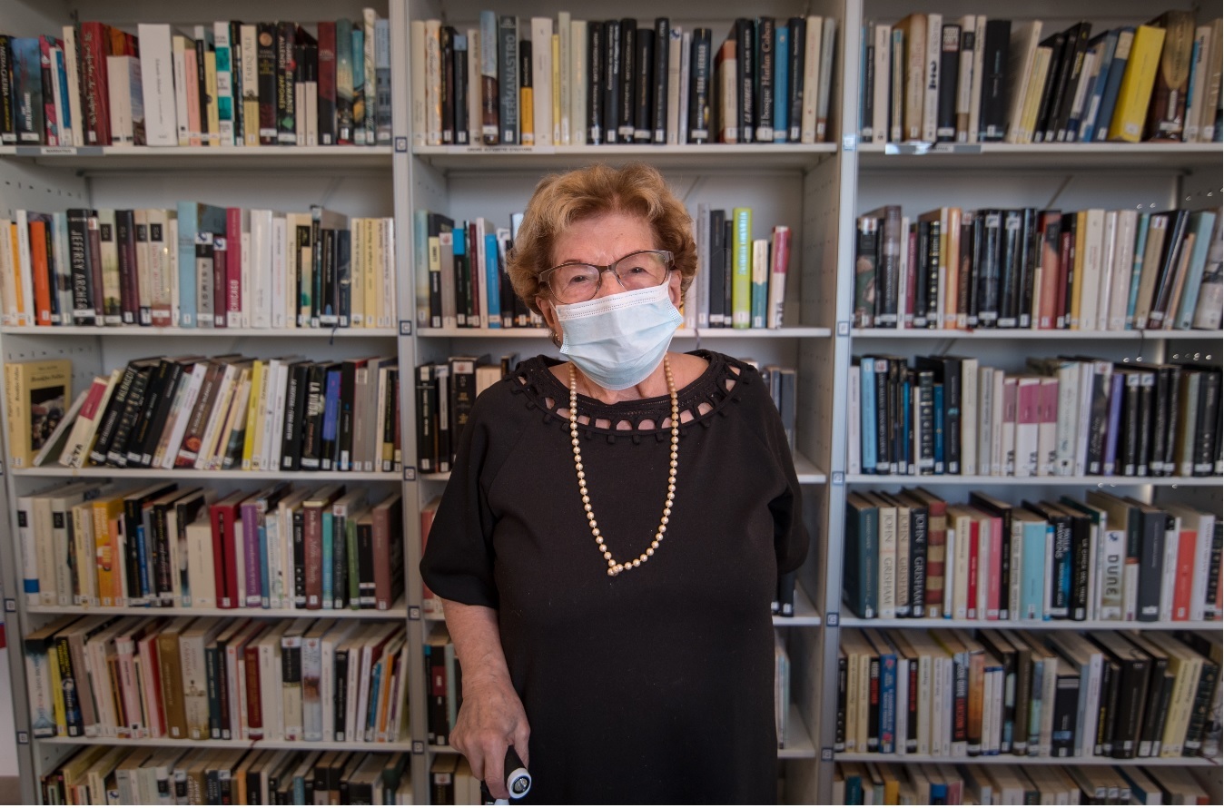 Yolanda posa delante de una estantera de libros en la biblioteca donde es socia.