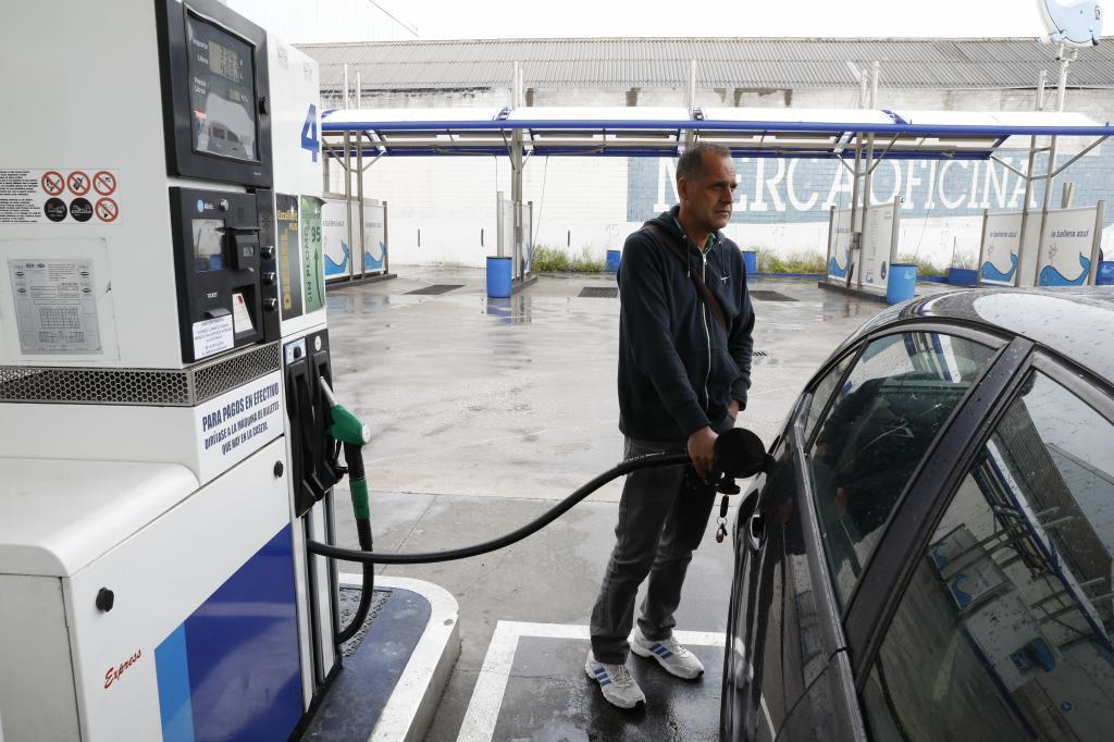 Un hombre llena el depósito de combustible del coche en el surtidor de una gasolinera.