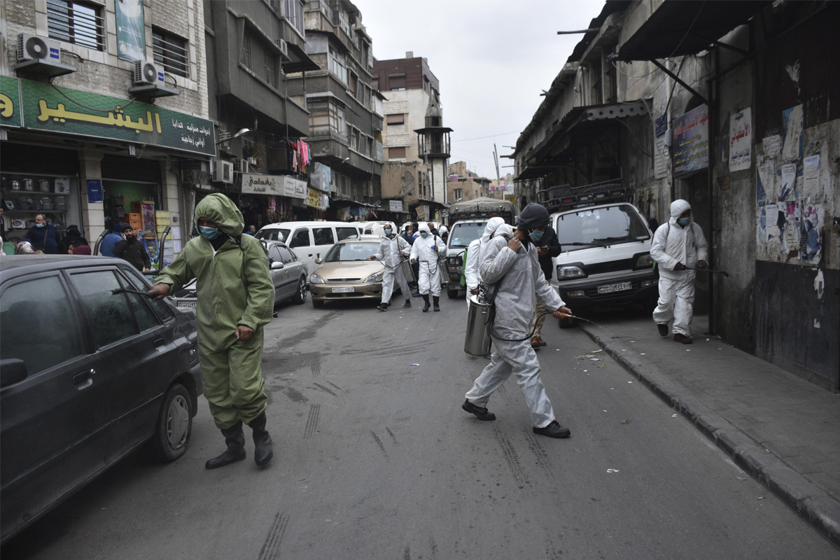 Trabajadores rocían productos desinfectantes en las calles de Damasco.