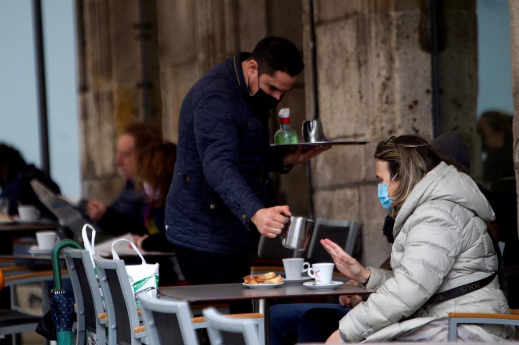 Un camarero sirve un caf en la terraza de un bar en Vigo.