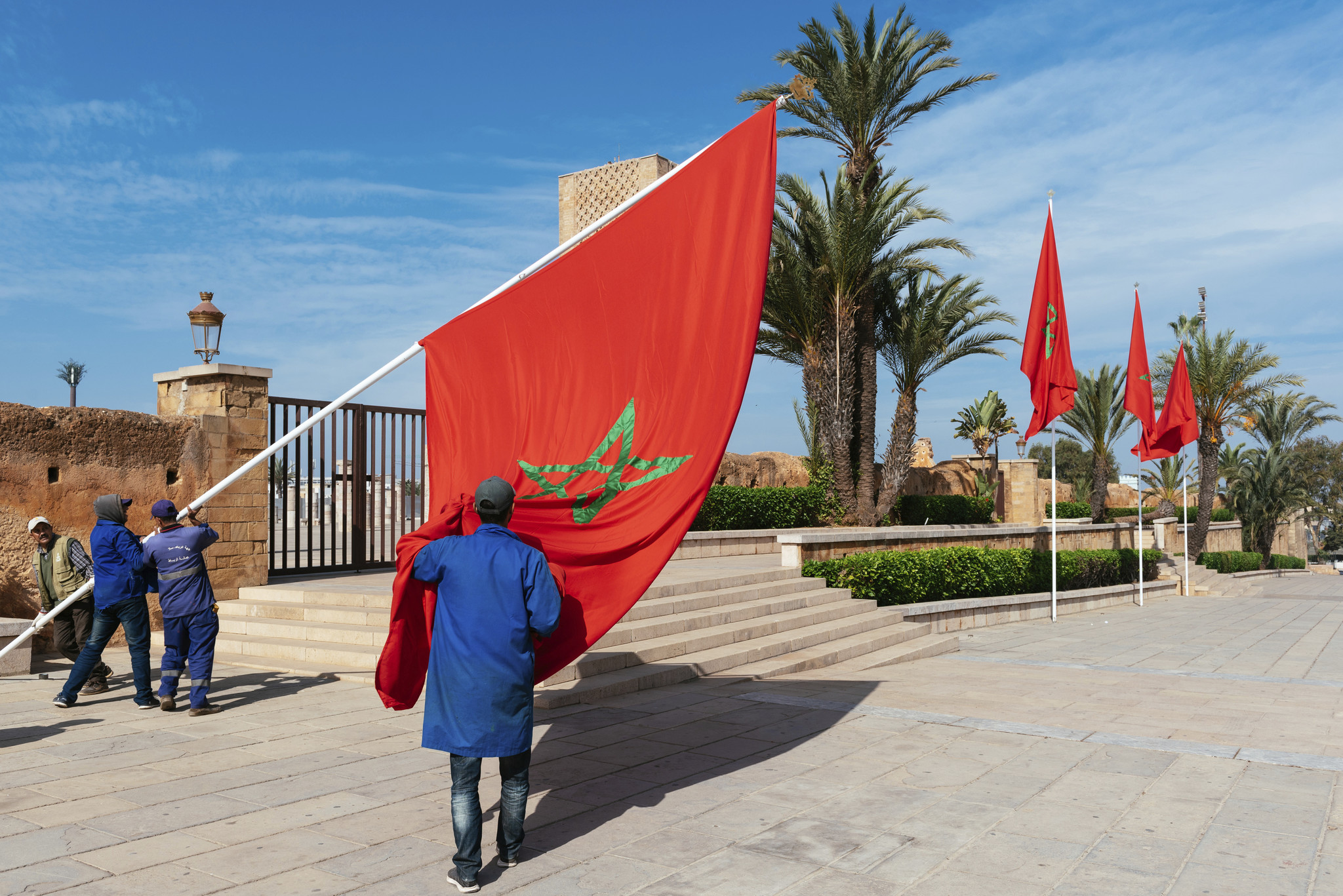 hombres colocan la bandera de Marruecos en frente de la Hassan Tower.
