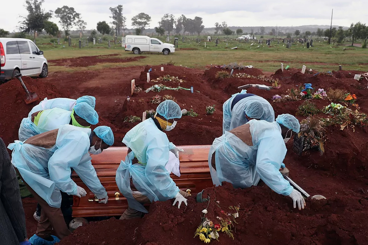 Trabajadores funerarios entierran a un fallecido por coronavirus en una tumba recién excavada en el cementerio de Olifantsvlei, cerca de Johannesburgo, en Sudáfrica.